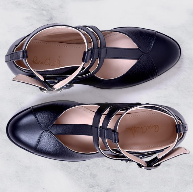 Black sandals with strap details on a light gray background