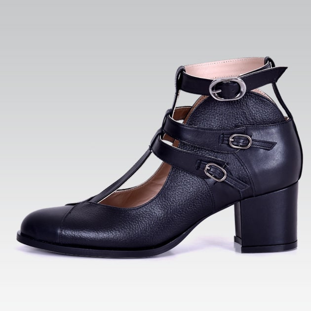 Black leather shoe with buckles on a gray background