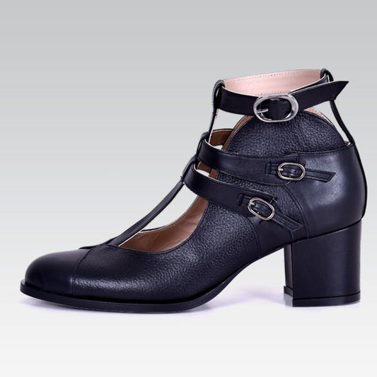 Black leather shoe with buckles on a gray background